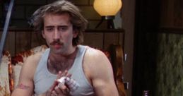 Nicolas Cage in "Raising Arizona," seated with a meal and a drink, captures a moment of comedic intensity in the film.