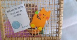 Colorful basket containing "Balaio de Gato" story sequencing cards and a cute cat figure for creative learning activities.