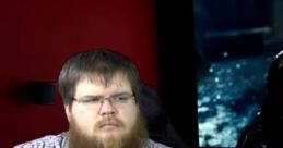 Angry Joe Show discussion featuring a man with glasses and a beard, expressing a serious demeanor in a studio setting.