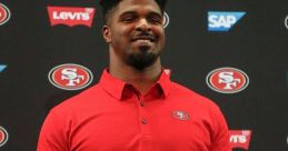 Dee Ford in a red San Francisco 49ers polo shirt holding a 49ers helmet at a press event, showcasing his team pride.