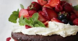 Delicious chocolate cake layered with whipped cream and topped with fresh strawberries, raspberries, and blueberries.