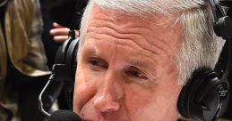 Mike Breen provides live commentary at a basketball game, wearing a suit and headset, focused on the action.