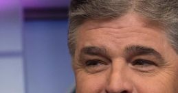 Sean Hannity smiling on set, wearing a suit and tie, with a backdrop reflecting a professional news environment.