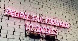 Neon sign on a white brick wall stating "People fail forward to success," inspiring a growth mindset. Perfect for motivating teams.