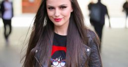 Cher Lloyd showcases a stylish look with a graphic tee, leather jacket, and red plaid pants, exuding confidence and charisma.