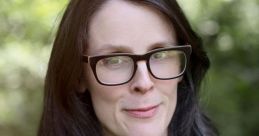 Portrait of a woman with long dark hair and glasses, wearing a green top, outdoors in a natural setting.