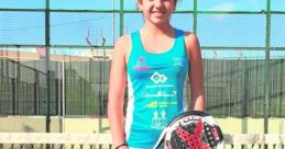 Nuria from Spain, dressed in sporty attire, poses with her paddle and smiles on a tennis court, showcasing her athleticism.