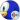 Close-up of Sonic the Hedgehog showcasing his iconic blue fur, vibrant green eyes, and playful expression against a blue sky.