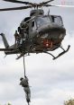 Soldier rappelling from a UH-1 helicopter during a tactical operation, showcasing military agility and aerial maneuverability.