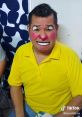 Que chistoso cocolito: man with humorous clown makeup, bright yellow shirt, smiling playfully for TikTok video.