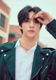 Hyunjin from Stray Kids poses confidently outdoors, showcasing a stylish look with a sleek jacket and silver accessories.