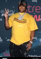 Excited attendee at the Streamy Awards wearing a bright yellow Balenciaga shirt, flashing a peace sign on the red carpet.