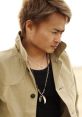 Jin Hashimoto stylishly dressed in a beige jacket and layered necklaces, showcasing a confident expression outdoors.