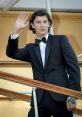 Nikolai from Primis BO3 waves while wearing a tuxedo, showcasing elegance on a stylish staircase.