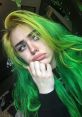 Young content creator with vibrant green and yellow hair, expressing a thoughtful mood. Perfect for RUS Feofilov fans.