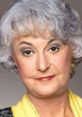 Bea Arthur with her iconic gray hair and yellow attire, showcasing her renowned style and strong persona.