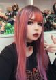 Egirl with vibrant pink and purple hair, choker, and stylish makeup, surrounded by figurines, showcasing unique style.