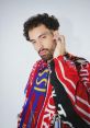 JeanJass showcases his unique style in a vibrant scarf, highlighting his artistic flair and Belgian hip-hop culture.