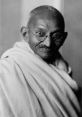 Mahatma Gandhi smiling, wearing traditional attire, embodying peace and nonviolent resistance in black and white photography.