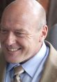 Hank Schrader smiling in a formal outfit, showcasing his charismatic personality and confident demeanor.