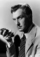 Vincent Price in a classic black and white portrait, holding a vintage camera with a mysterious expression.