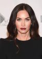 Megan Fox showcasing stunning makeup with bold lips and glamorous hairstyle at a red carpet event.