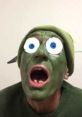 Surprised man with green face paint and oversized eyes, expressing shock, wearing a green hat and sweater.