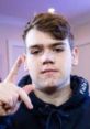 Mongraal confidently poses with a hand sign, showcasing his unique personality and connection to gaming culture.