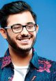 CarryMinati smiling in a vibrant floral shirt against a blue background, showcasing his charismatic personality.