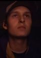 Concentrated young man with headphones, gazing intently, reflecting focus and determination in a dimly lit environment.