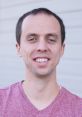 Smiling man in a maroon shirt, highlighting Jared Owen's approachable personality and engagement in his work.