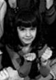 Young girl with dark hair in black and white, showcasing her playful expression, reminiscent of Danielle Brisebois’ charm.