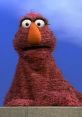 Telly Monster, a beloved character voiced by Martin P. Robinson, displaying curiosity with a vibrant red fur coat.