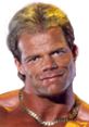 Lex Luger smiling confidently, showcasing his muscular physique and iconic look from his wrestling career.