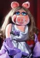 Miss Piggy from Sesame Street in an elegant silver dress, showcasing her iconic style with glamorous gloves and a floral brooch.