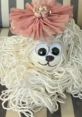 Cute handmade dog craft with yarn fur, large googly eyes, and a pink flower accessory, ideal for DIY enthusiasts.