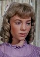 Close-up of Nellie Oleson, portrayed by Alison Arngrim, showcasing her distinct hairstyle and expression in a vintage scene.