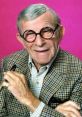 George Burns smiling with glasses, dressed in a checked suit against a vibrant pink background, exuding classic Hollywood charm.