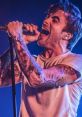 Anthony Green passionately performing live, showcasing his tattoos and intense vocal energy during a Circa Survive concert.