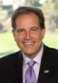 Jim Nantz smiling in a suit and tie, showcasing his charm during a professional broadcast event.