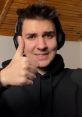 Smiling young man giving a thumbs up while wearing headphones, representing positivity and engagement in streaming culture.