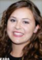 Smiling young woman with curly hair and vibrant eyes, representing Kara Saunders in a professional setting.