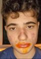 Teen with orange sauce on lips and cheeks, looking surprised. Fun messy eating moment with Spizee snacks.