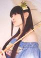 Yukari Tamura styled in traditional attire, holding a bamboo umbrella, exuding a serene and thoughtful expression.