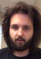 Close-up of a man with long hair and a beard, expressing thoughts for PhilipSoloTV content creation.