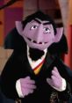 Count Von Count, the beloved purple vampire puppet, enthusiastically counts while wearing a classic tuxedo.