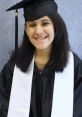 Smiling graduate in cap and gown, proudly wearing white stole, celebrating academic achievement and new beginnings.