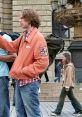 Casual traveler in an orange jacket navigates a busy street, reminiscent of adventures in EuroTrip (2004).