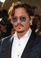 Johnny Depp wearing sunglasses and a stylish suit, showcasing his iconic look at a red carpet event.