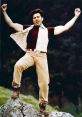 Sunny Deol strikes a triumphant pose on a rock, showcasing his iconic style and charisma in a natural setting.